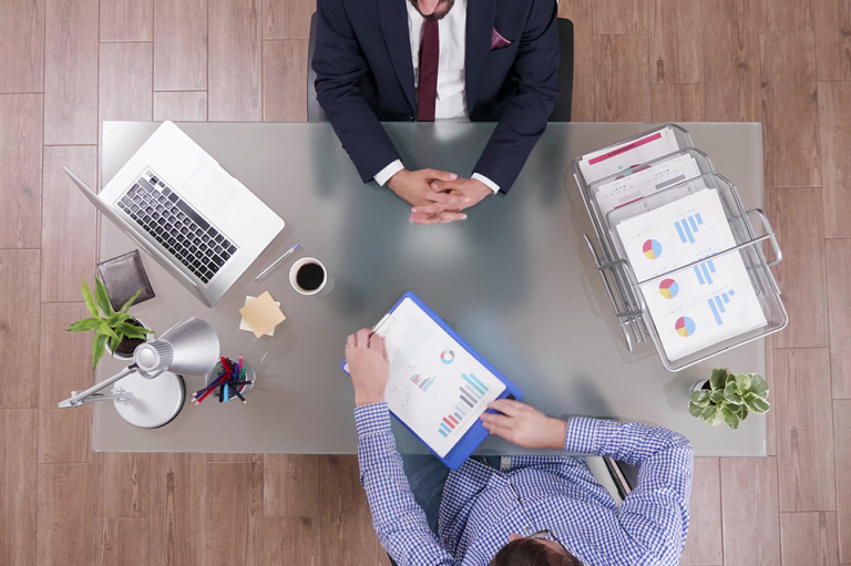 Vue de dessus d'un rendez-vous de conseil, deux personnes autour d'un bureau avec graphiques et documents
