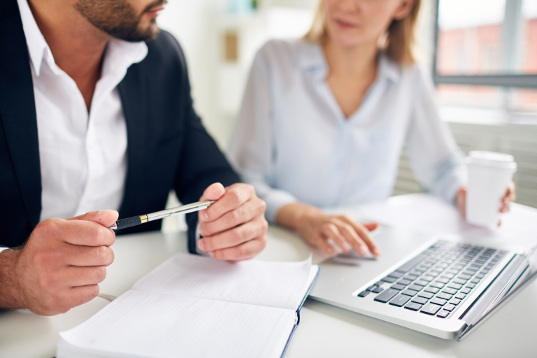 Deux personnes en rendez-vous de travail autour d'un ordinateur portable et de documents
