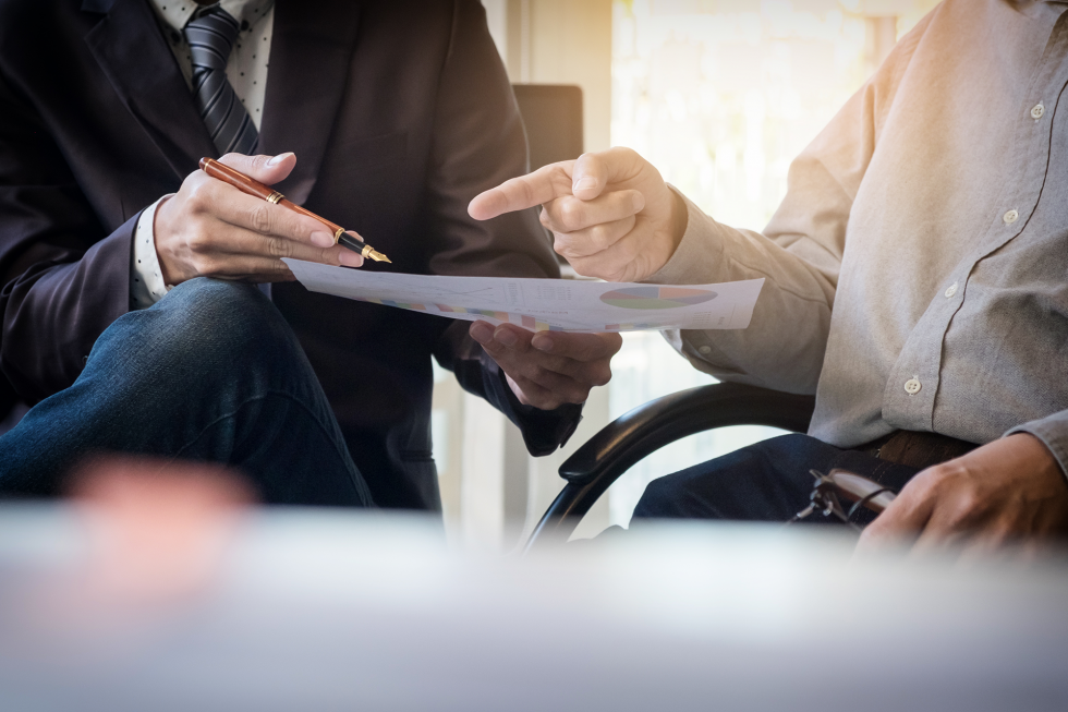 Conseiller présentant un document à un client, stylo à la main